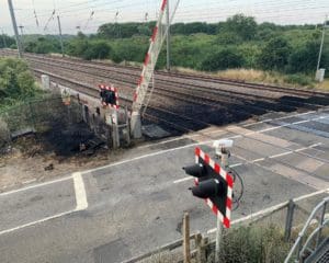 The aftermath of a fire on railway tracks, by a rail crossing. Black covering the tracks where the fire had been.